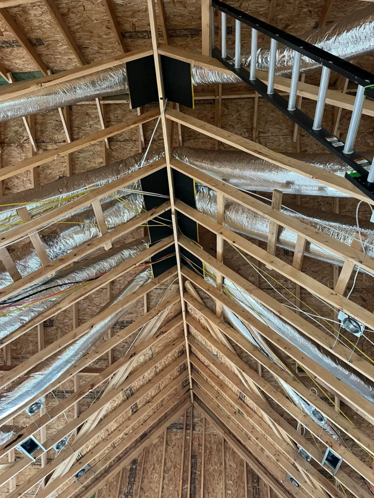 Complex HVAC ductwork installation in cathedral ceiling showing professional routing and support