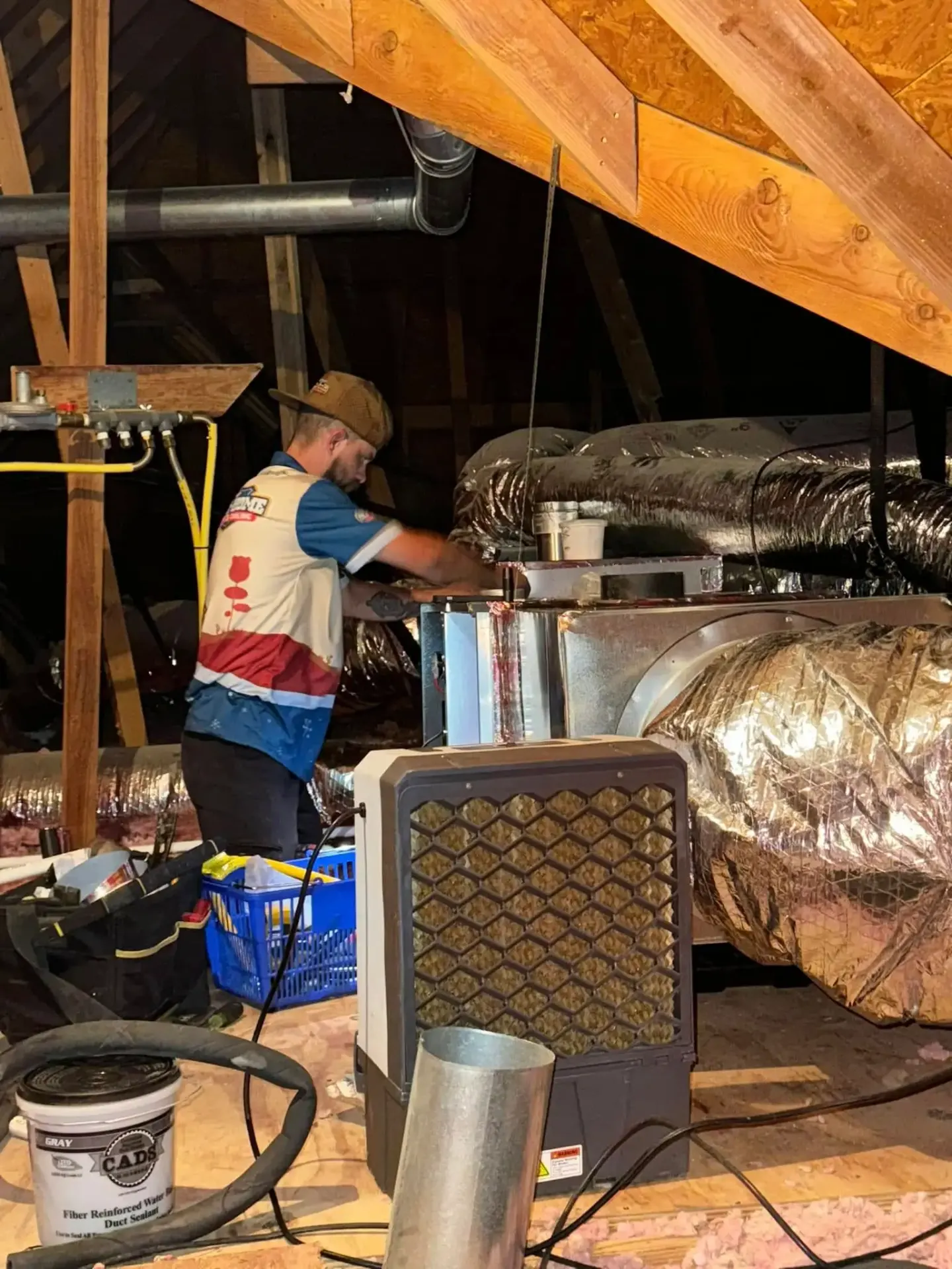 Licensed HVAC technician inspecting attic ductwork before professional cleaning service in Broken Arrow